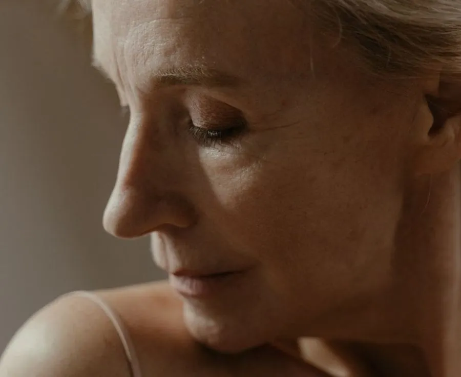 Close-up of a woman's cheek and defined jawline in soft light