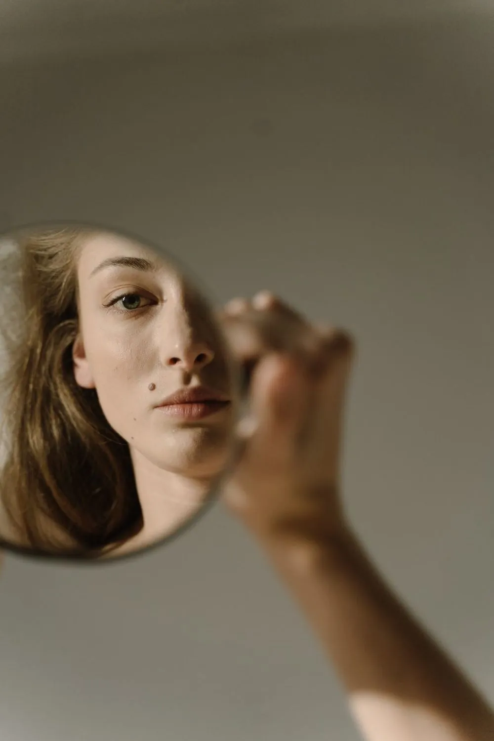 Woman looking at her skin in a hand mirror